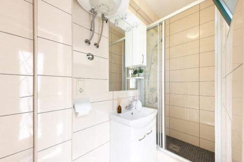 uma casa de banho branca com um lavatório e um espelho em House Natura em Gornji Seget