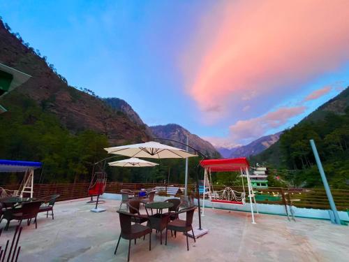 柯索的住宿－Hotel New Panchali With Mountain view By Winterline, Kasol，庭院里的一组桌子和遮阳伞