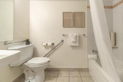 a white bathroom with a toilet and a sink at Hotel Faubourg Montreal Centre-Ville Downtown in Montréal