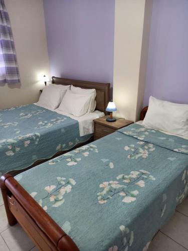 1 dormitorio con 2 camas y manta azul con flores en Korasida Blue Coast, en Akhladherí
