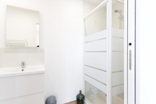 ein weißes Badezimmer mit einem Waschbecken und einem Spiegel in der Unterkunft Le Noyer - appartement moderne & accessible in Montaigu-Vendée
