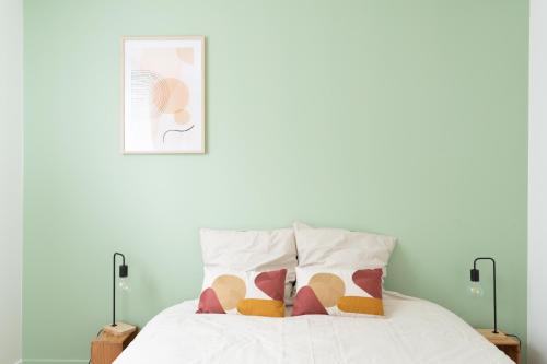 ein Schlafzimmer mit einem weißen Bett mit einem Bild an der Wand in der Unterkunft Le Noyer - appartement moderne & accessible in Montaigu-Vendée