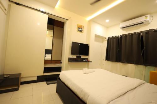 - une chambre avec un lit et une télévision dans l'établissement Hotel Parashar Palm, à Nagpur