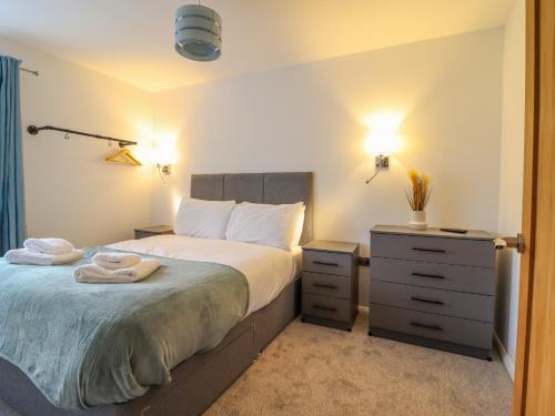 a bedroom with a bed and a dresser with towels on it at 1 Ty Newydd in Porthmadog