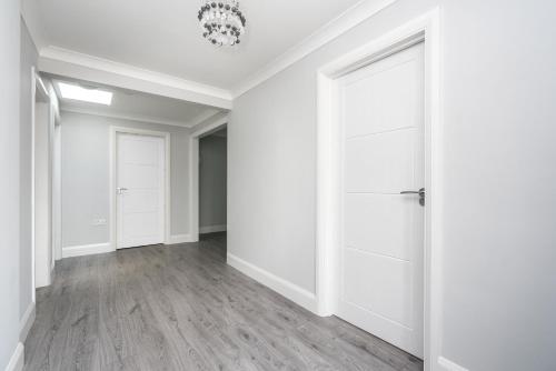 Copthorne的住宿－Lovely Modern Room，空的走廊,有白色的墙壁和白色的门