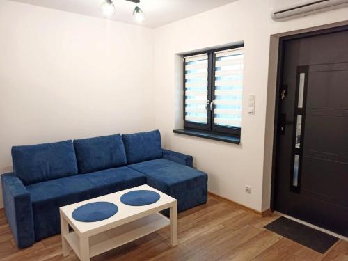 uma sala de estar com um sofá azul e uma mesa em Apartamenty 4You 3 em Zator