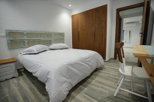 a bedroom with a white bed and a desk and a table and chair at La touche Bleue in Sfax