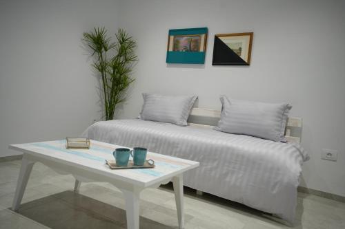 uma cama branca e uma mesa com duas canecas em La touche Bleue em Sfax