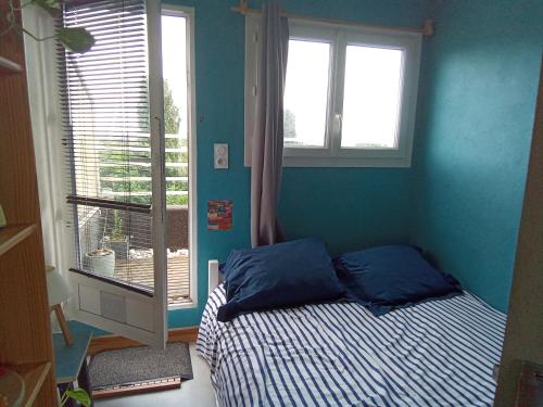 - une chambre avec un lit aux murs bleus et une fenêtre dans l'établissement Appartement Centre ville Terrasse, à Tarbes