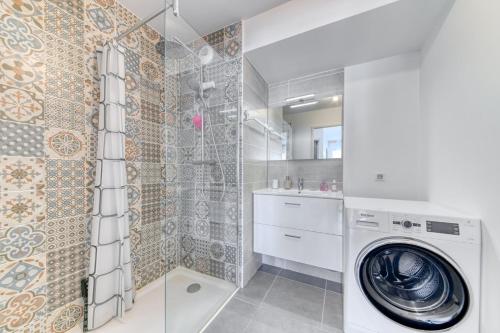 La salle de bains est pourvue d'un lave-linge et d'une douche. dans l'établissement GuestReady - Apt. Lumineux à Villeurbanne, à Villeurbanne