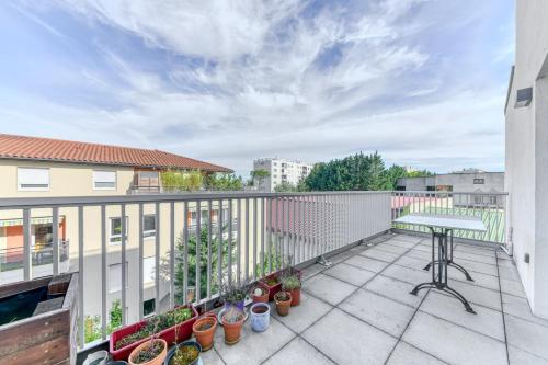 d'un balcon avec une table et des plantes en pot. dans l'établissement GuestReady - Apt. Lumineux à Villeurbanne, à Villeurbanne