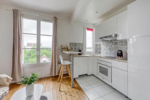 a kitchen with white cabinets and a table and window at T2 à 100m du centre - 10 min de Paris - 400m du lac et Casino d'Enghien - Gare d'Enghien à 10m in Enghien-les-Bains