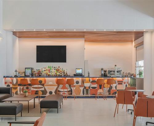 a restaurant with a bar with orange chairs at Hotel Santamarta in Cullera
