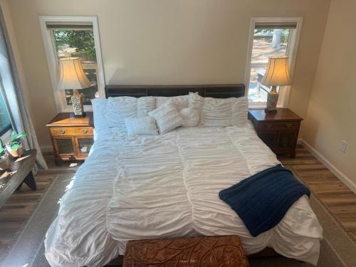 a large bed in a bedroom with two windows at Cottage style home close to golfing and lake 