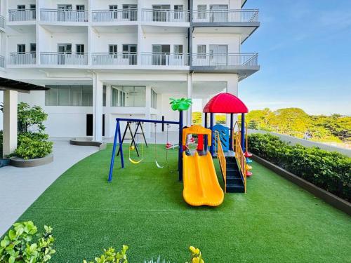 a playground on a lawn in front of a building at WV 8 Serene Family Room in Iloilo City