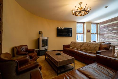 a living room with a leather couch and a tv at The Mash Tun in Aberlour