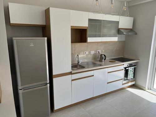 a kitchen with white cabinets and a sink and a refrigerator at Sweet 1-bedroom penthouse in the heart of it all in Il-Gżira