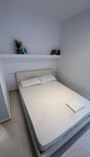 a small white bed in a room with a shelf at Sweet 1-bedroom penthouse in the heart of it all in Il-Gżira