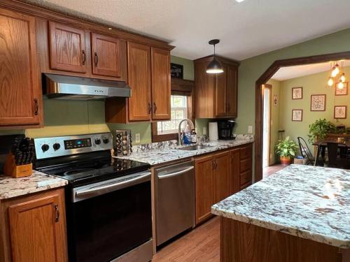 a kitchen with wooden cabinets and a stove top oven at Hocking Hills Cabin-Private Hot Tub, Hiking, Caves in Rockbridge