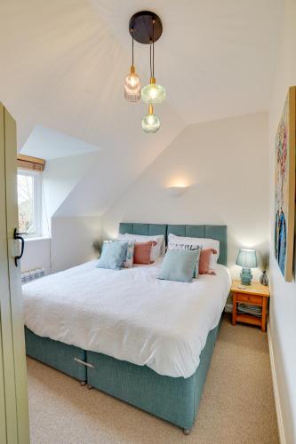 a bedroom with a large bed with blue pillows at Toad Hall Pet-Friendly Family Stay, Lake Access in Somerford Keynes