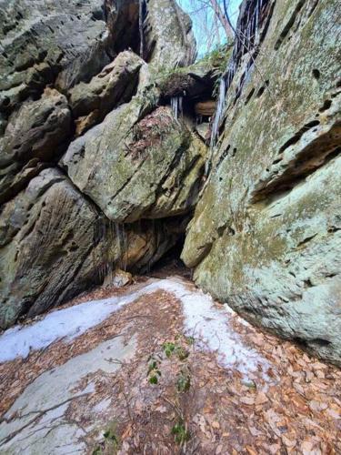 a rock wall with snow on the ground next to it at Hocking Hills Cabin-Private Hot Tub, Hiking, Caves in Rockbridge