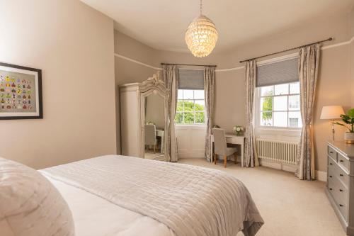 a bedroom with a bed and a desk and windows at Queens Circus - Montpellier, Central Cheltenham in Cheltenham