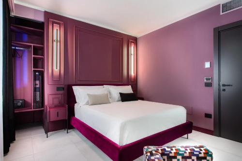 una camera con letto bianco e pareti viola di Welmy Napoli a Napoli