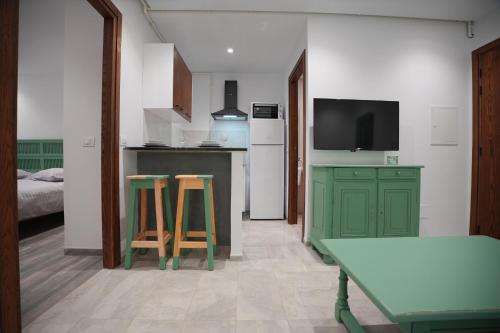 スファックスにあるLe vert Emeraudeのキッチン(緑のキャビネット、テーブル、スツール2脚付)