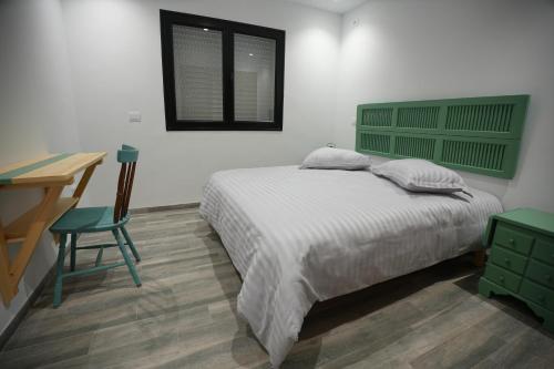 a bedroom with a bed with a green headboard and a desk at Le vert Emeraude in Sfax