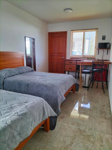 a bedroom with two beds and a desk and a table at KC Hotel & Suites in Comitán