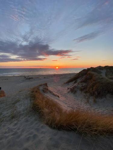 een zonsondergang op een strand met de oceaan op de achtergrond bij Borestranda - Nytt strandhus med 6 sengeplasser! in Klepp