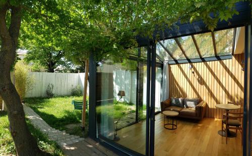 a glass house with a couch and a tree at Le mazet des amants, cabane en bois avec jacuzzi privatif in Avignon