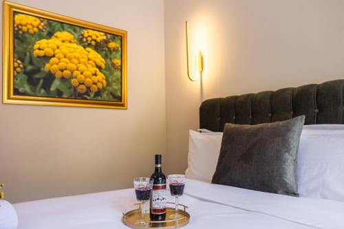 a bottle of wine and two glasses on a bed at FLOARA DI MUNTE Forest Luxury Suites in Metsovo