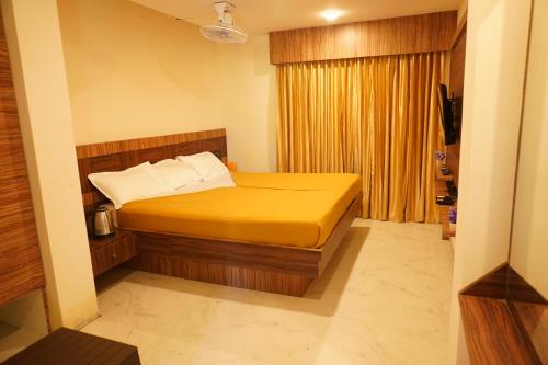 a bedroom with a bed with yellow sheets and a window at Shree Mantra Residency and Homestay in Yercaud
