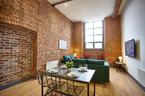 un soggiorno con divano verde e parete in mattoni di The Ruby Suite a Manchester