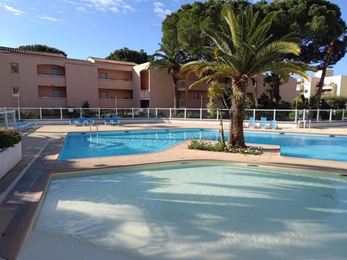 une grande piscine avec un palmier en face d'un bâtiment dans l'établissement Magnifique 2 pièces Piscine Parking Plage à pied Tennis, à Vallauris