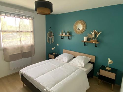 une chambre avec un grand lit avec un mur bleu dans l'établissement T2 cosy 4 places RDC - jardin, à Lons