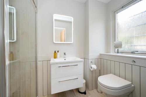 a white bathroom with a toilet and a shower at Greenwood - Stunning Scandinavian Style Home in the heart of Ballater Royal Deeside in Ballater