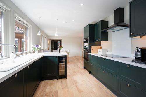 a kitchen with green cabinets and a white counter top at Greenwood - Stunning Scandinavian Style Home in the heart of Ballater Royal Deeside in Ballater