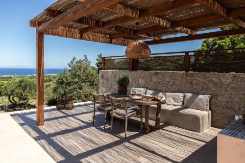a patio with a couch and a table with chairs at Montesea - Luxury Nature Villas in Vasilikos