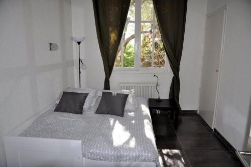 un lit blanc dans une chambre avec une fenêtre dans l'établissement Villa de charme 5 pièces vue mer, à Antibes