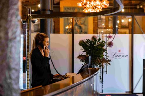a woman talking on a cell phone at a counter at Titanic Hotel Liverpool in Liverpool
