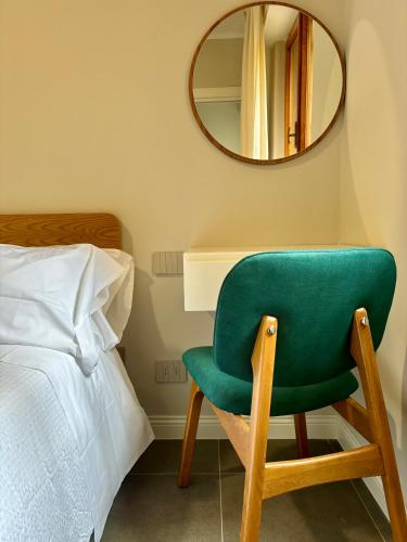 a green chair sitting next to a bed and a mirror at Camere di Bianca in Foligno