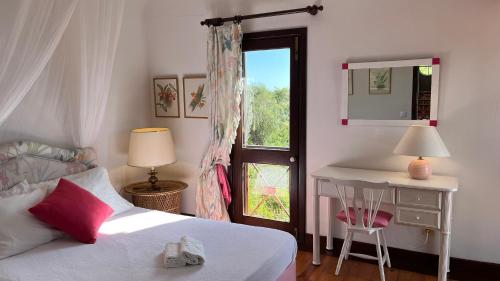 1 dormitorio con cama, escritorio y ventana en Quinta das Acácias perto do Meco, en Sesimbra