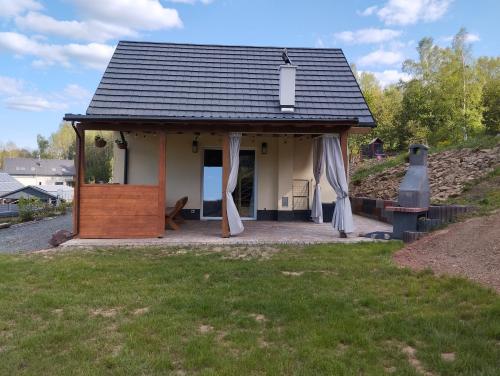 een klein huis met een veranda met een dak bij Leśna Ostoja in Lubawka