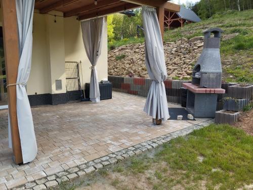 a patio with a fireplace and curtains on it at Leśna Ostoja in Lubawka