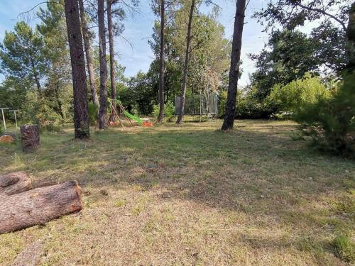 un parc avec des arbres et une bûche dans l'herbe dans l'établissement les papillons, à Ruoms