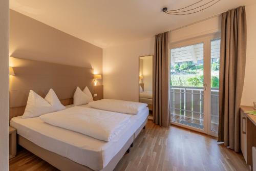 a bedroom with a bed and a large window at Tirolerin Garni Hotel in Termeno