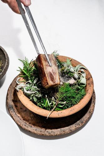 a bowl of food with a piece of meat and herbs at Boutique Hotel Boškinac in Novalja