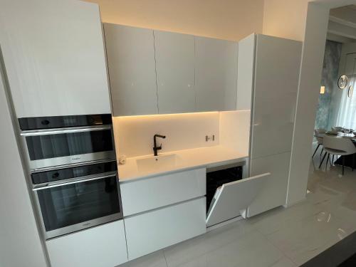 a kitchen with white cabinets and a sink at Haus Margarete - Attico Infinity Vista Mare con Jacuzzi - Agenzia Cocal in Caorle